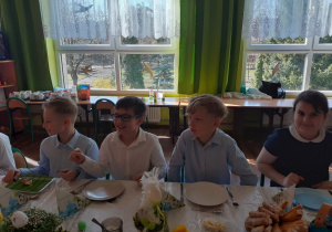 Uczniowie spożywają wielkanocne potrawy.